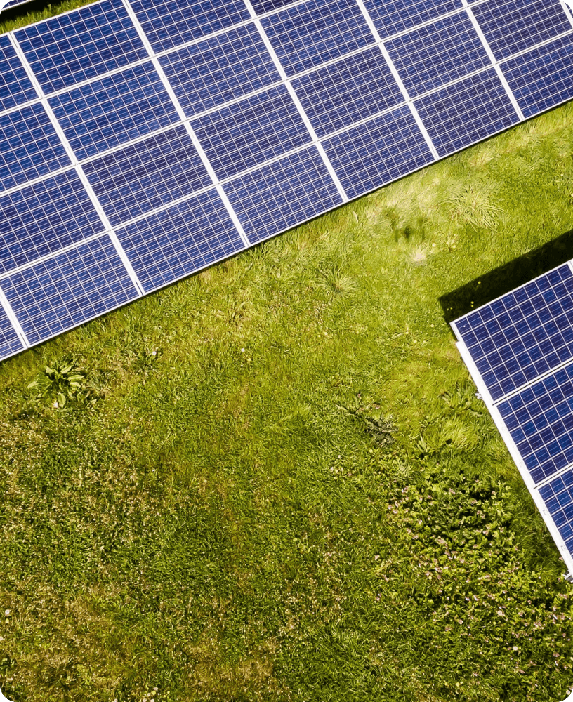 Aerial view of solar panels installed on a neatly kept grassy area, positioned at slightly different angles to maximize sunlight absorption—sparking curiosity about solar energy questions.